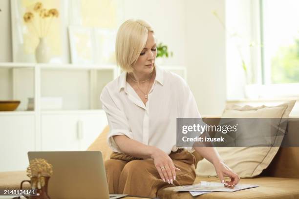 mature woman using laptop at home - cream coloured shirt stock pictures, royalty-free photos & images
