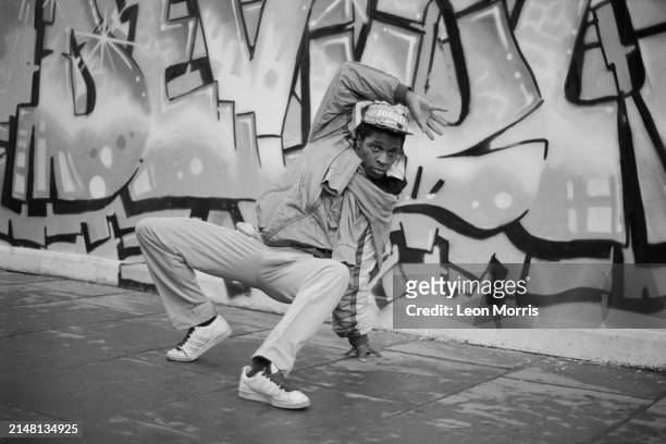 Breakdancer in action against graffiti 'Devious' by graffiti crew The Trailblazers , Covent Garden, London, 1985.