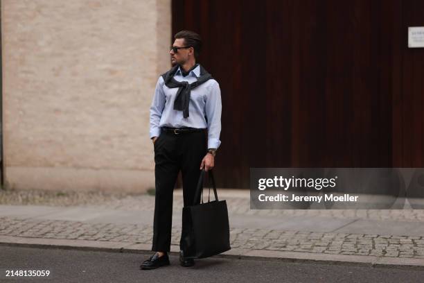 André Hellmundt seen wearing Saint Laurent black sunglasses, Olymp light blue cotton buttoned shirt, Olymp grey knit sweater, Drykorn black long suit...