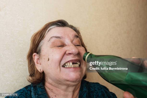 destitute adult woman uses teeth to pry open a metal bottle cap - gingivitis stock-fotos und bilder