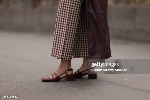 Aline Kaplan seen wearing Sézane beige / brown checked long pants, YOOX burgundy leather long coat and Sézane burgundy shiny leather heeled...