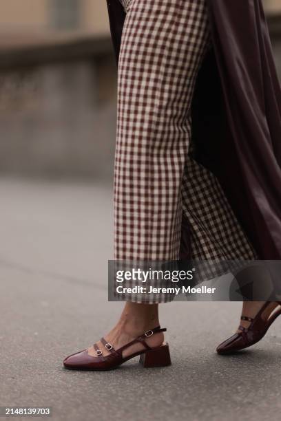 Aline Kaplan seen wearing Sézane beige / brown checked long pants, YOOX burgundy leather long coat and Sézane burgundy shiny leather heeled...