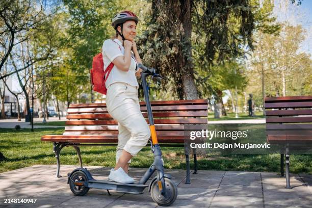 young beautiful woman putting safety helmet on before riding electric scooter in the city - sports helmet stock pictures, royalty-free photos & images