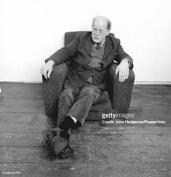English painter Carel Weight seated in an armchair in a studio at the Royal College of Art in Kensington, London in 1983.