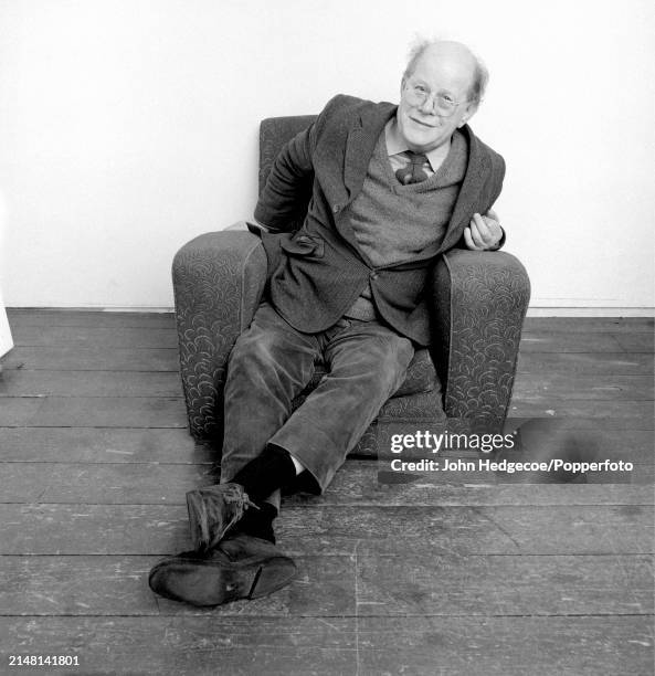 English painter Carel Weight seated in an armchair in a studio at the Royal College of Art in Kensington, London in 1983.