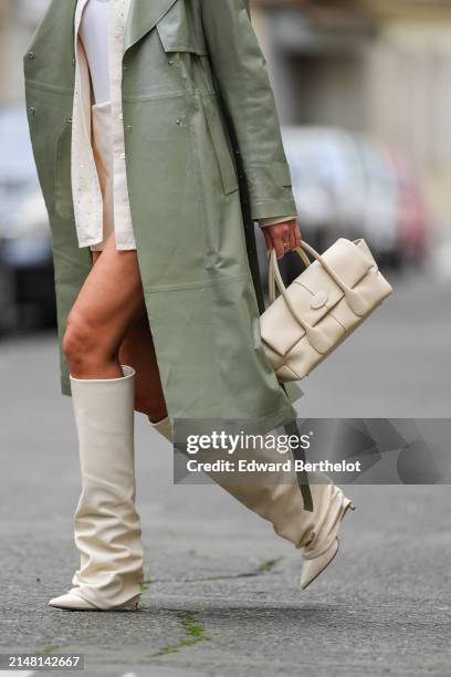 Katie Giorgadze wears a sage pastel green smooth leather trench coat from Mackage, a cream color / white leather bag from Tod's, pointed toe /...