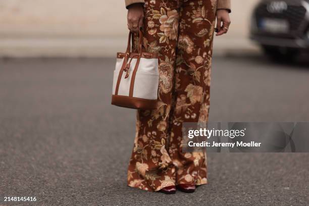 Aline Kaplan seen wearing Sézane yellow / brown flower pattern wide leg pants, Veronica Beard beige fabric / brown leather bag and Sézane burgundy...