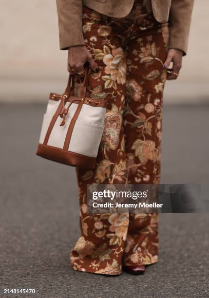 Aline Kaplan seen wearing Sézane yellow / brown flower pattern wide leg pants, Veronica Beard beige fabric / brown leather bag and Sézane burgundy...