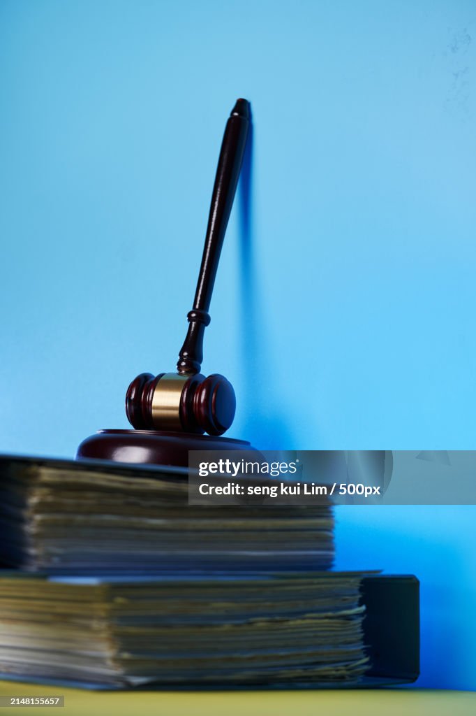 Close-up of gavel on books against blue background