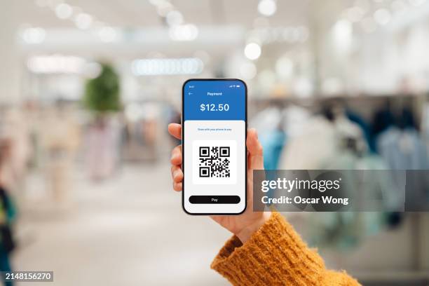 making qr code payment with smartphone in retail store - paid palabra en inglés fotografías e imágenes de stock
