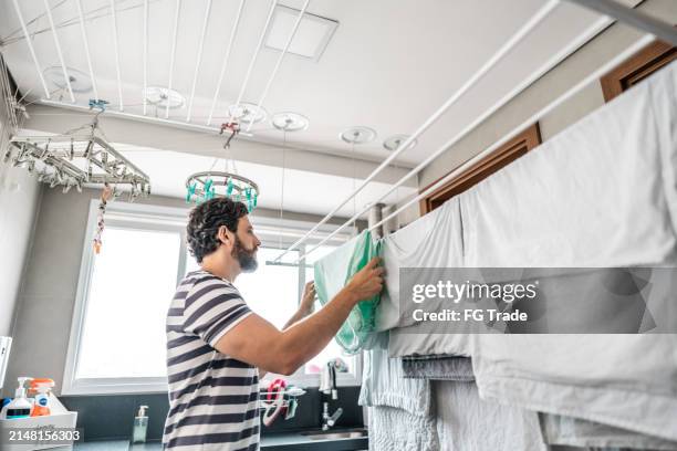 mid adult man hanging laundry on clothesline at home - draped stock pictures, royalty-free photos & images