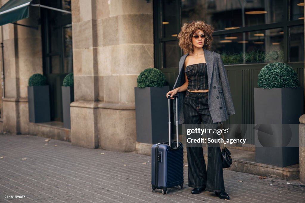 Femme élégante avec valise dans la rue de la ville