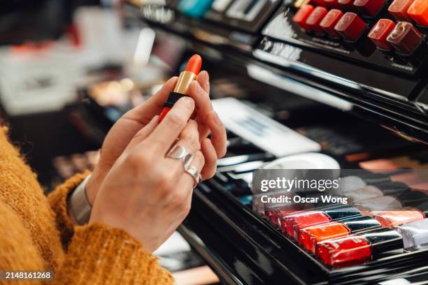 closeup of female hand choosing lipstick shades at beauty store - läppstift bildbanksfoton och bilder