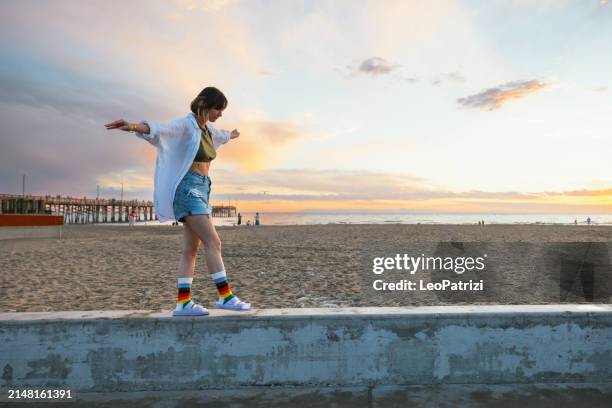 personne portant des chaussettes arc-en-ciel pendant le mois de la fierté marchant sur la plage - justice sociale concept photos et images de collection