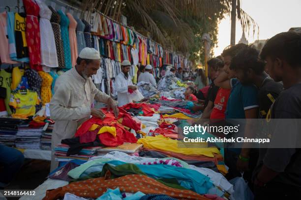 Man sells clothes to a group of young men on the street ahead of Eid al-Fitr on April 10, 2024 in Bengaluru, India. Muslims worldwide observe the Eid...