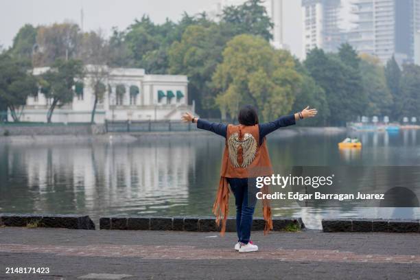 mexican woman feeling free, opens her arms in front of a lake - chapultepec stock pictures, royalty-free photos & images