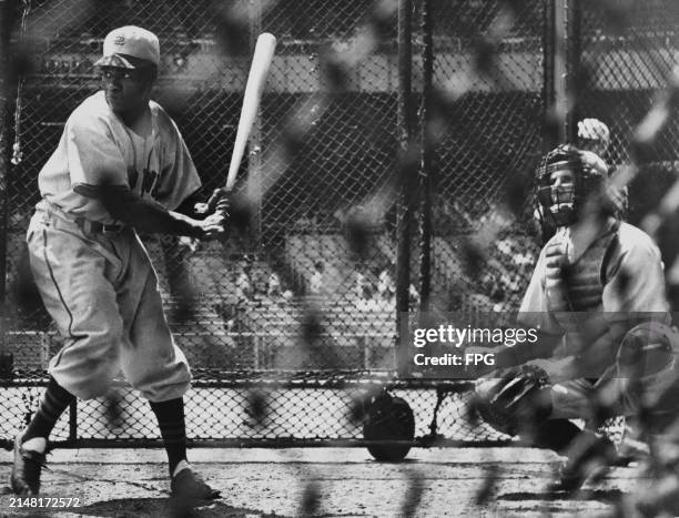 Willard Brown , Outfielder for the St Louis Browns swings at warm up pitches in the batting cage with catcher Les Moss before their Major League...