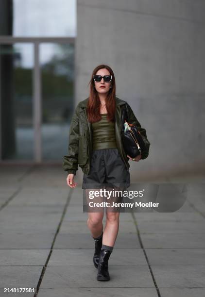 Dariia Prokopovych seen wearing Prada black / white sunglasses, khaki green leather tube top, Prada black nylon logo shorts, khaki green leather...