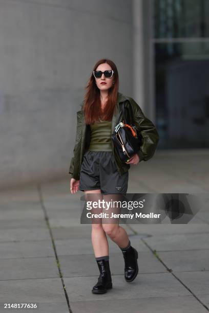 Dariia Prokopovych seen wearing Prada black / white sunglasses, khaki green leather tube top, Prada black nylon logo shorts, khaki green leather...