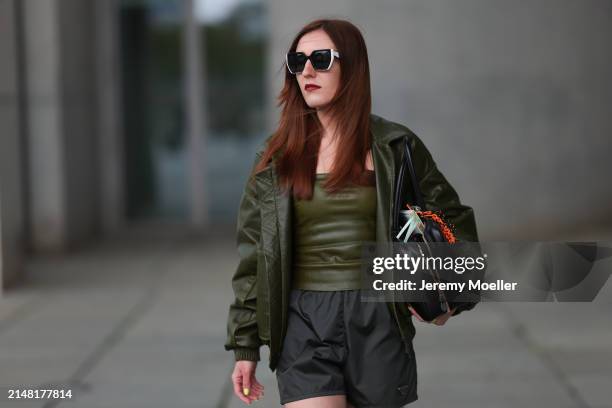 Dariia Prokopovych seen wearing Prada black / white sunglasses, khaki green leather tube top, Prada black nylon logo shorts, khaki green leather...