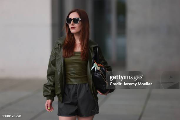 Dariia Prokopovych seen wearing Prada black / white sunglasses, khaki green leather tube top, Prada black nylon logo shorts, khaki green leather...