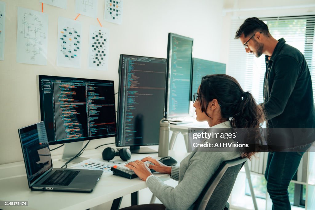 Two Hispanic Programmers Collaborating in Modern Office