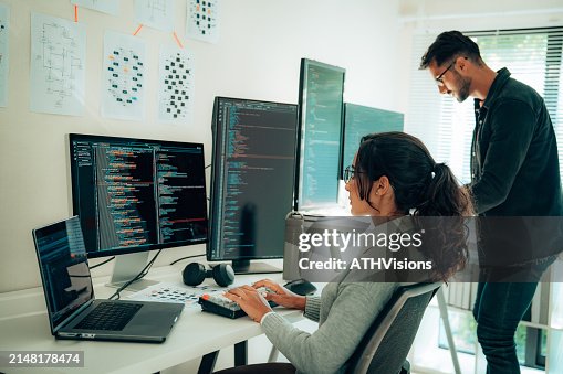 Dos programadores hispanos colaboran en una oficina moderna Dos programadores hispanos colaboran en una oficina moderna