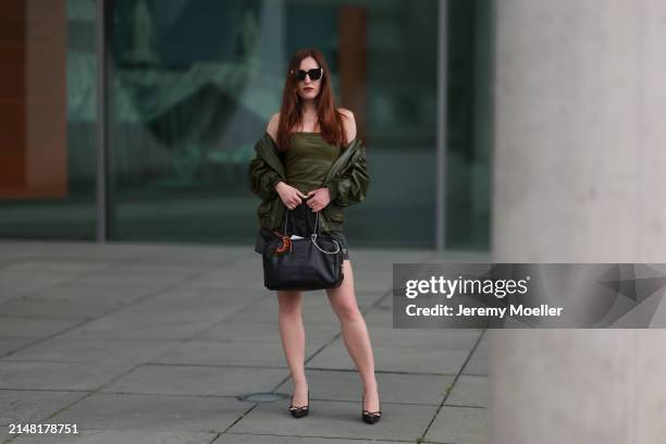 Dariia Prokopovych seen wearing Prada black / white sunglasses, khaki green leather tube top, Prada black nylon logo shorts, khaki green leather...