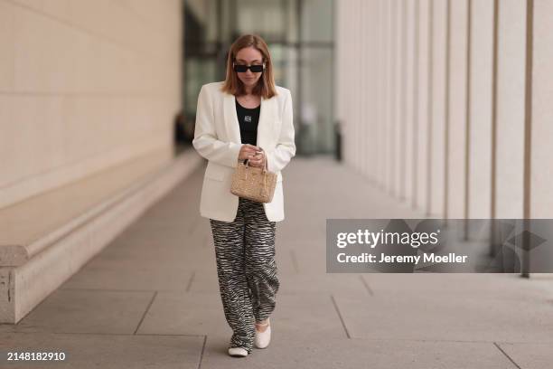 Sonia Lyson seen wearing Gucci black sunglasses, Loewe black cotton logo embroidered top, H&M white / black zebra animal print pants, Zara white...