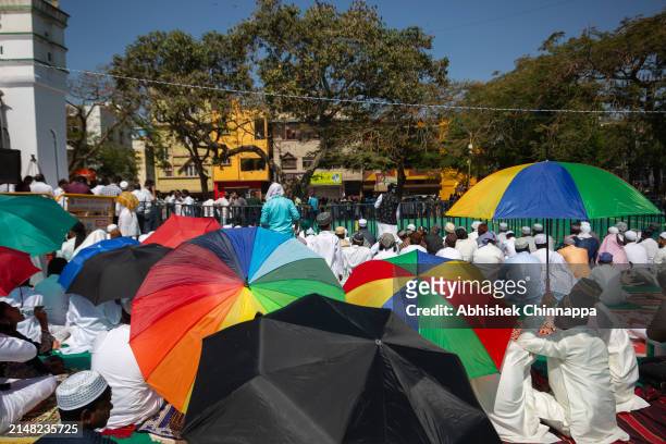 Muslims sit under umbrellas and listen to a sermon after Eid al-Fitr prayers in a public playground on April 11, 2024 in Bengaluru, India. Muslims...