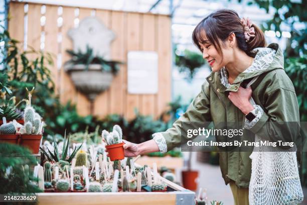 eco-friendly gardening: young asian woman shopping for potted plants in gardening centre - flora environment stock pictures, royalty-free photos & images