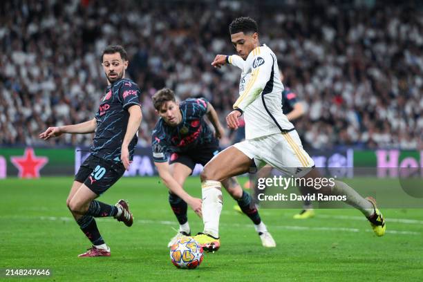 Jude Bellingham of Real Madrid CF competes for the ball with Bernardo Silva of Manchester City during the UEFA Champions League quarter-final first...