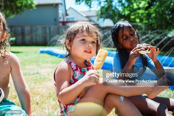 eurasian toddler girl eating ice cream with friends outside - chinese eating backyard stock pictures, royalty-free photos & images