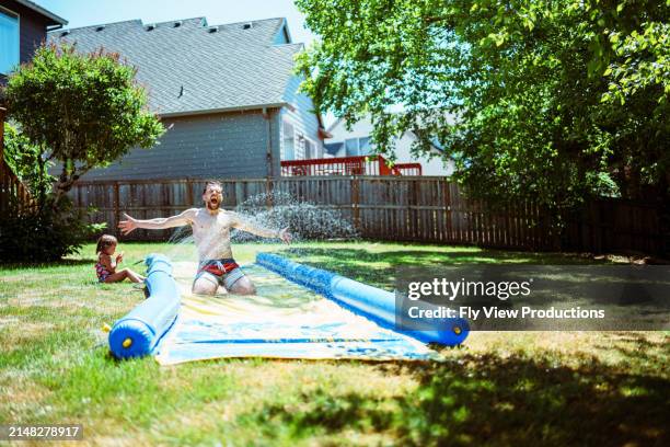 man having fun on slip n slide while playing outside with his daughter - hot american girl stock pictures, royalty-free photos & images