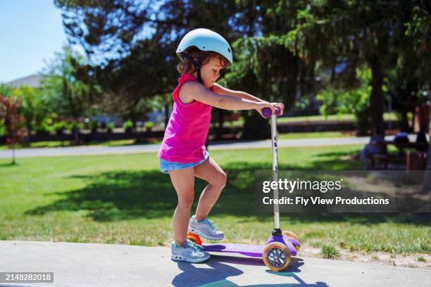 cute eurasian girl riding scooter at the skate park - scooter for toddler girl stock pictures, royalty-free photos & images