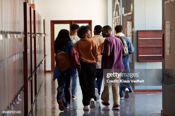 teenage students talking while walking in corridor - inside locker stock pictures, royalty-free photos & images
