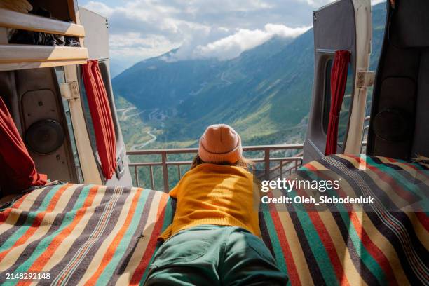 woman laying in camper van overlooking furka pass in switzerland - caravan stockfoto's en -beelden