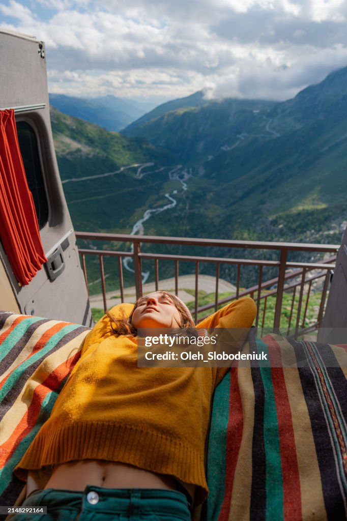 Woman laying in camper van overlooking Furka Pass in Switzerland