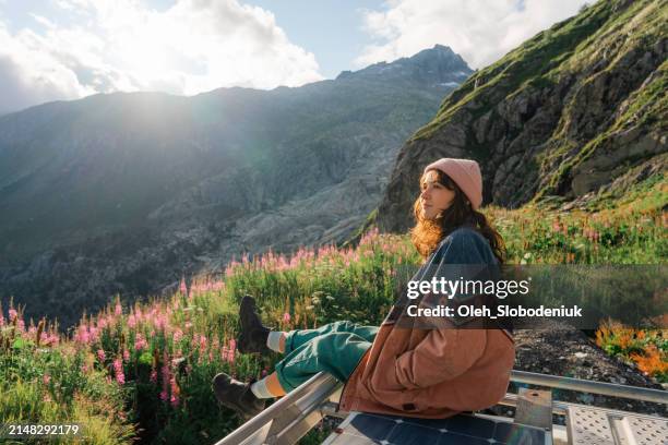 woman sitting on rooftop of camper van overlooking furka pass - kanton wallis stock-fotos und bilder