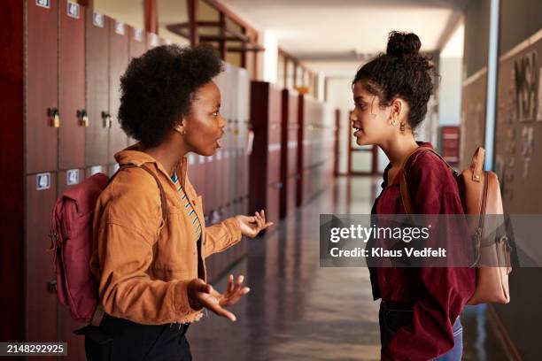female teenage students discussing in corridor - se disputer photos et images de collection