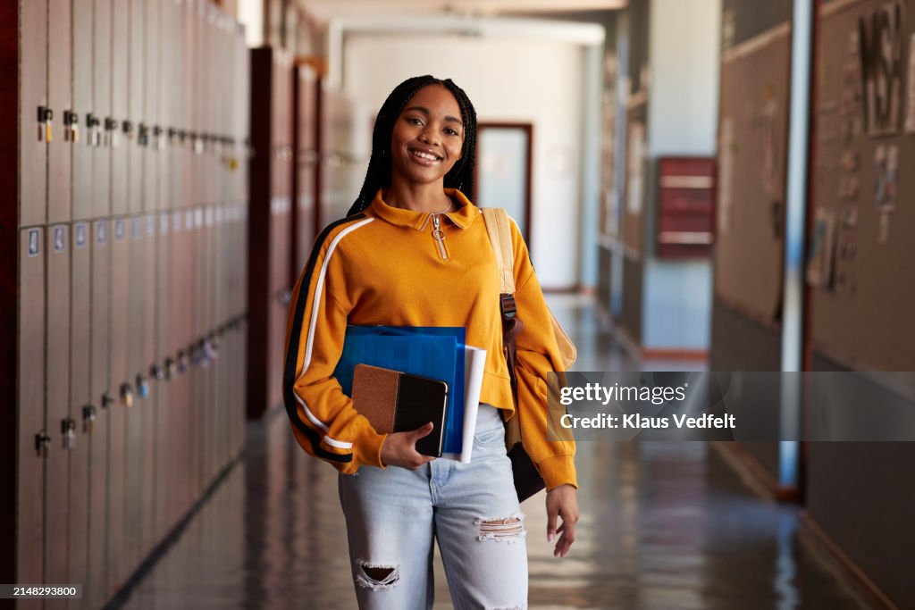 Smiling female student with books in hallway