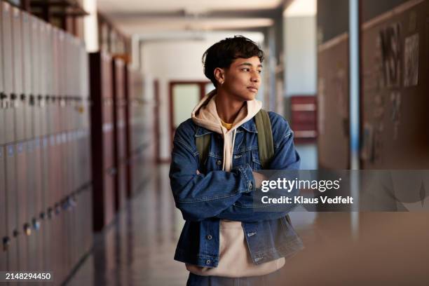 teenage boy with arms crossed looking away in corridor - 16 17 anos - fotografias e filmes do acervo
