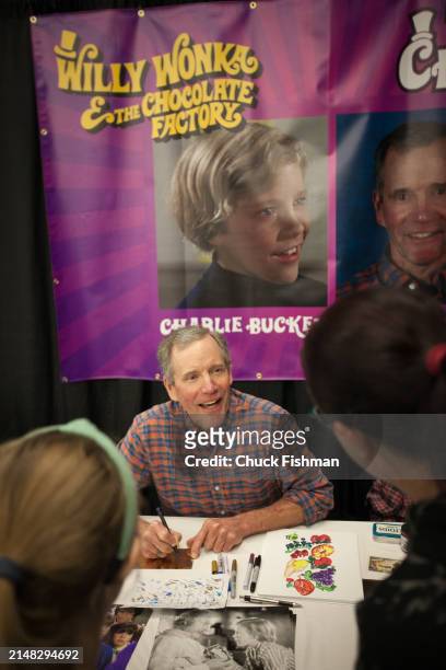 American actor Peter Ostrum signs an autograph for attendees during an event related to the film 'Willie Wonka and the Chocolate Factory' at the...