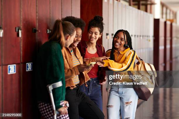 happy friends leaning on lockers sharing smart phone - tears happiness stock pictures, royalty-free photos & images