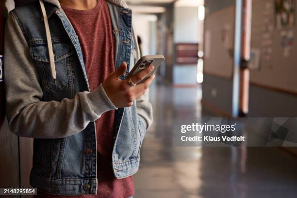 teenage boy with mobile phone leaning in corridor - unrecognizable person stock pictures, royalty-free photos & images