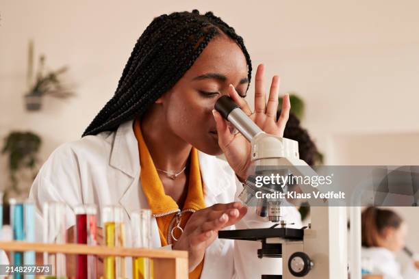 transgender student looking through microscope in classroom - laboratory glassware stock pictures, royalty-free photos & images
