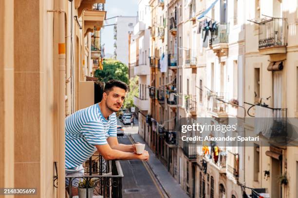 man drinking coffee on the balcony on a sunny morning, barcelona, spain - southern european descent stock pictures, royalty-free photos & images