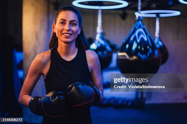 schöne junge boxerin trainiert mit einem boxsack im trainingsfitnessstudio. - kickboxen stock-fotos und bilder