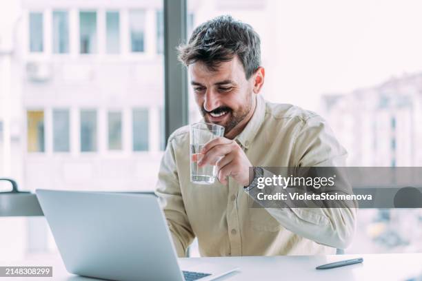 erfolgreicher geschäftsmann im modernen büro, der am laptop arbeitet. - wasser trinken stock-fotos und bilder