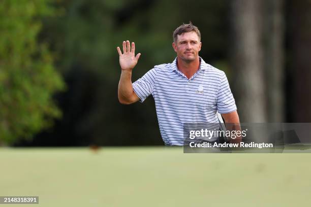 Bryson DeChambeau of the United States acknowledges the crowd as he walks to the 18th green during the first round of the 2024 Masters Tournament at...